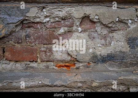 Old weathered brick wall with cracked plaster and peeling surface  Old weathered brick wall with cracked plaster and peeling surface Stock Photo