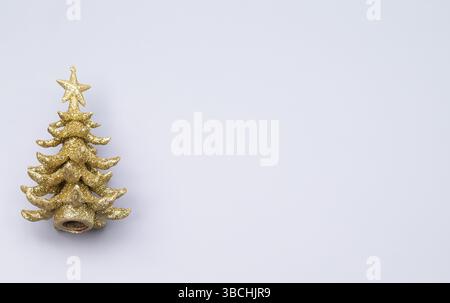 The photo shows a miniature golden Christmas tree against a grey background Stock Photo