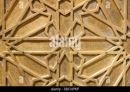 Golden metallic arabesque pattern. Islamic ornamental geometry. Decorative gilded surface background. Traditional Middle Eastern symmetrical design. Stock Photo