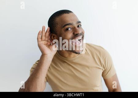 Curious Cheerful Black Man Holding Hand Near Ear Trying To Overhear Something Stock Photo