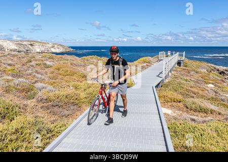 A cyclist walking his bike along the Cape Vlamingh Boardwalk beside Fish Hook Bay on the west coast of Rottnest Island, (Wadjemup) Western Australia, Stock Photo