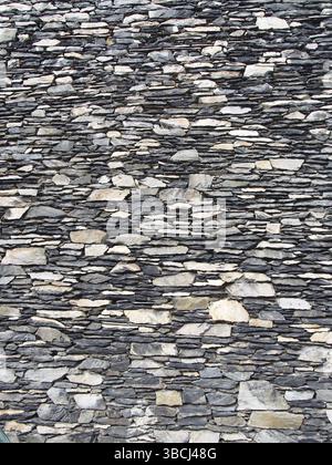 Old grey uneven stone wall made of stacked irregular pieces of rock Stock Photo