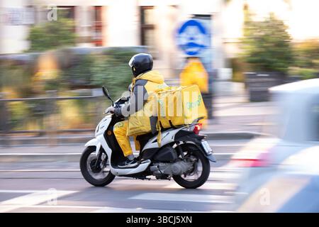 Belgrade, Serbia -  May 17, 2025: Glovo service courier with a delivery bag riding moto scooter in city street traffic Stock Photo