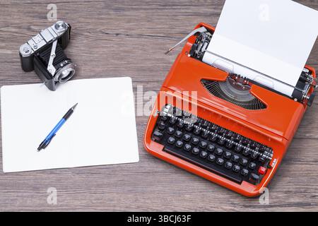 Analogue camera, notebook, pen and typewriter on a wooden table Stock Photo
