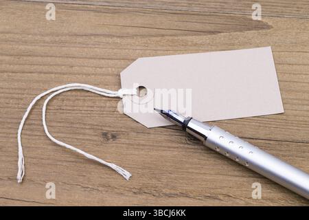 Image shows a blank label and a pen on a wooden table Stock Photo