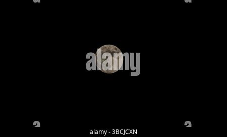 A bright full moon shines clearly against the dark night sky. Stock Photo