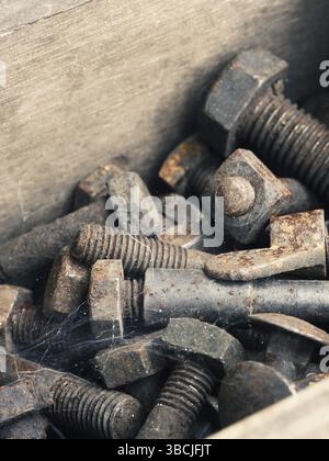 Old rusty bolts and nuts in a wooden box, industrial concept background Stock Photo
