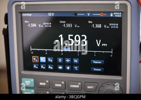 Close-up image of a digital Oscilloscope screen displaying voltage measurement in real-time. The interface shows a reading of -1.593V with various mea Stock Photo