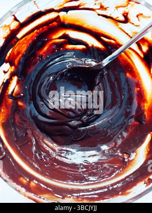 Delicious chocolate cream in glass jar on a white table. Preparing sweets concept. Directly above. Stock Photo