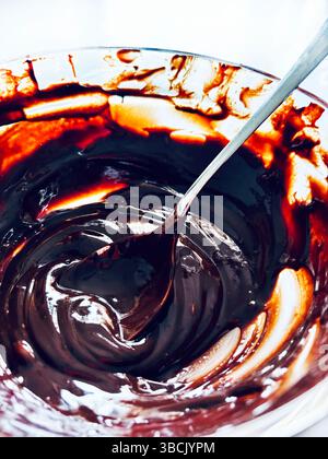 Delicious chocolate cream in glass jar on a white table. Preparing sweets concept. Directly above. Stock Photo