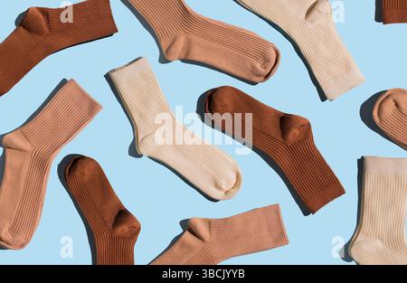 Colorful socks in shades of brown and beige are arranged on light blue background, highlighting their unique textures and patterns in visually appeali Stock Photo