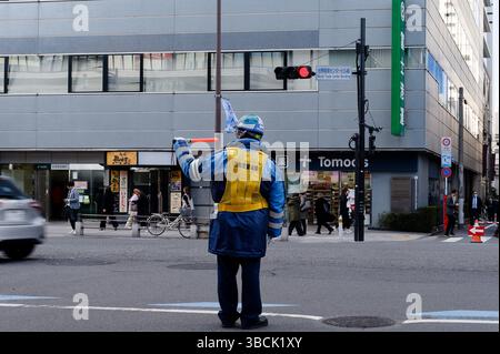 Traffic guard directs the flow near Tokyo’s World Trade Center Building Stock Photo