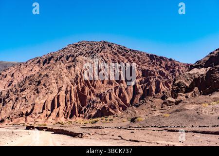 Colorful Geological Formations in Rainbow Valley Atacama Desert Chile Featuring Striking Red Earth Mineral Layers and Sandstone Mountains in a Breatht Stock Photo
