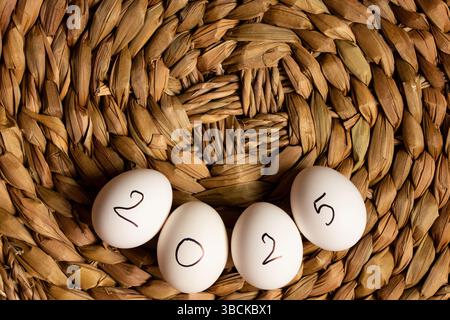 Eggs with the inscription 2025 lie on a straw wicker brown background, eggs Stock Photo