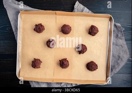 Eight Scoops of Chocolate-Cherry Cookie Dough on Sheet Pan: Balls of chilled cookie dough spaced out on baking sheet lined with parchment baking paper Stock Photo
