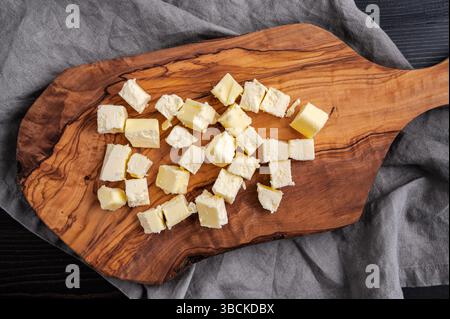 Cubed Pieces Of Butter on a Cutting Board: Stick of butter roughly chopped into small squares on a wooden chopping board Stock Photo