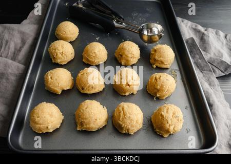 Scoops of Sugar Cookie Dough on a Sheet Pan: Non-stick baking pan with balls of cookie dough and a cookie scoop Stock Photo