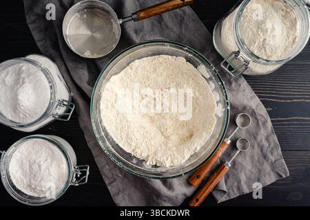 Directly Above a Bowl of Unbleached Flour with Jars of Ingredients: Glass bowl filled with flour with jars of baking powder and baking soda plus measu Stock Photo