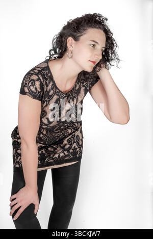 Three quarter length portrait of a young female in her mid twenties with black hair, and wearing a black dress Stock Photo