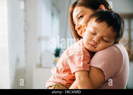 A tender loving biracial mother cradles her small sleeping newborn in her arms Stock Photo