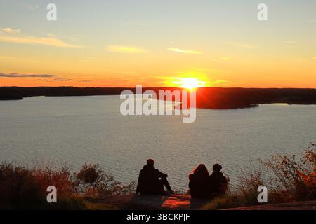 Sunset over the Swedish lake Malaren. People enjoying the last sun beams. Sunny dramatic and amazing horizon. Nice sky in September. Rear view. Stock Photo