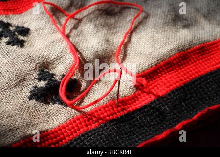 A red and black colored threads are using to make a handmade mat, the mat is in making process. Stock Photo