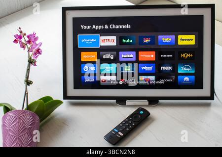 San Francisco, CA, May 20, 2025: Amazon Echo Show displays app icons on white table with Fire TV remote and orchid in a smart home setup. Stock Photo
