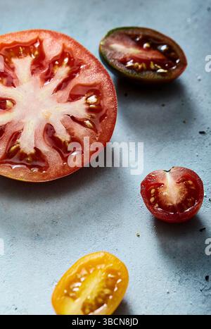 Assorted sliced tomatoes on a light blue textured surface Stock Photo