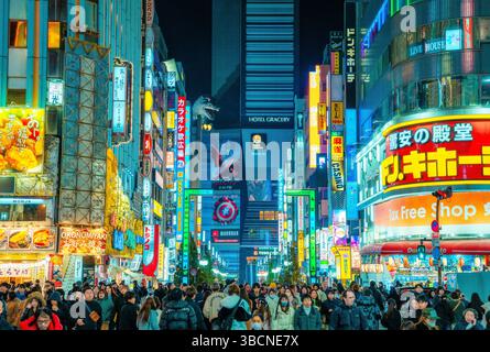 High-resolution photo capturing the bustling nightlife of Shinjuku, Tokyo, Japan. The image features glowing neon signs, busy streets, and the dynamic Stock Photo