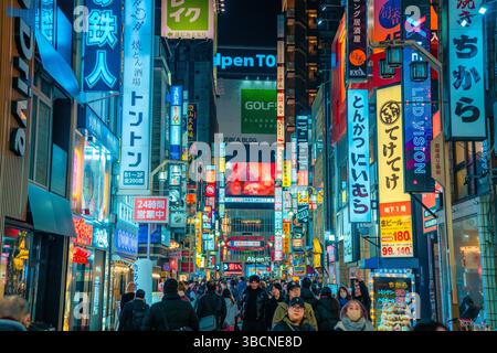 High-resolution photo capturing the bustling nightlife of Shinjuku, Tokyo, Japan. The image features glowing neon signs, busy streets, and the dynamic Stock Photo
