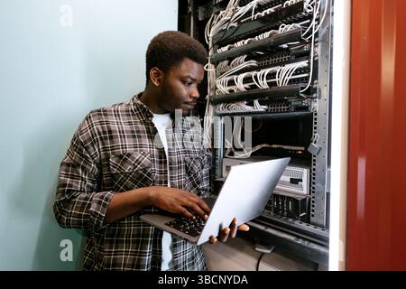 Technician configuring server settings in a data center during the day Stock Photo