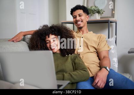 Relaxed Couple Enjoying Time Together While Using a Laptop at Home Stock Photo
