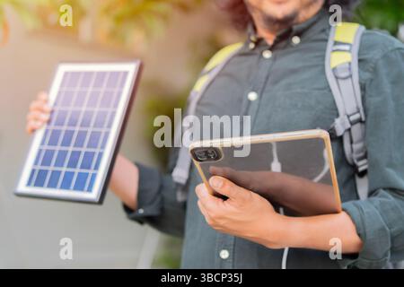 Engineer using portable solar panel for charge his tablet pc for working outside the area. Portable solar charing technology concept. Stock Photo