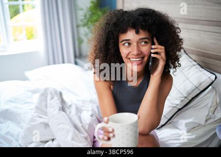 Young Woman Relaxing at Home With Coffee and Having a Phone Conversation Stock Photo