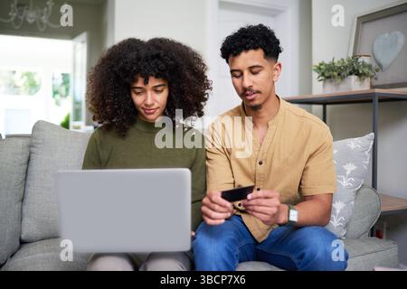 Couple Managing Finances Together Using Laptop and Credit Card at Home Stock Photo
