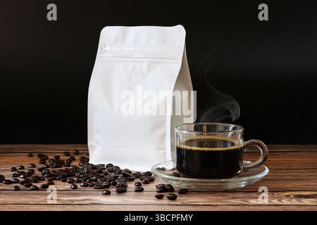 Roasted coffee beans in white paper bag with zipper on wooden table, blank mockup coffee bag template for product design advertising, black coffee Stock Photo