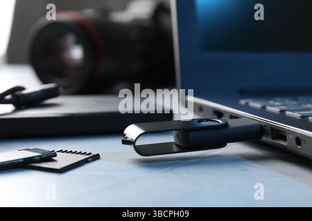 Flash drive connected to laptop and SD memory cards on gray textured table, closeup Stock Photo