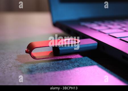 USB flash drive connected to laptop on dark grey table, closeup Stock Photo