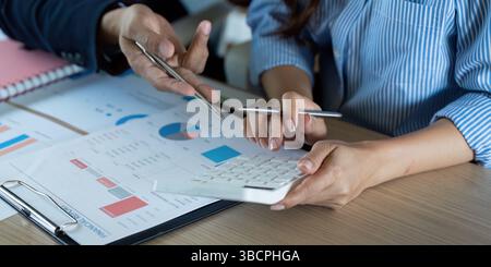 Collaborative Financial Discussion. Professionals analyzing data with calculators and spreadsheets. Stock Photo