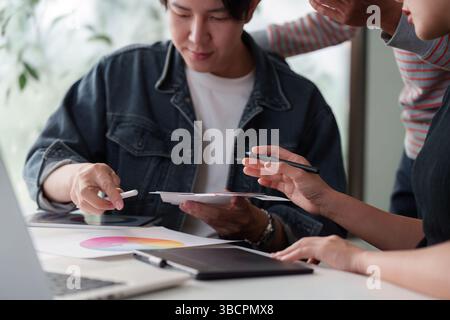 Collaborative Creativity and Visual Design. An interactive team session focused on UX UI with digital devices and lively discussion. Stock Photo