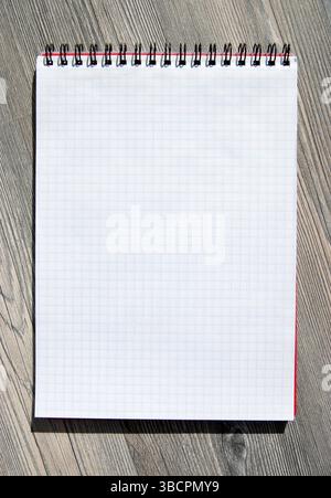 A blank notebook on a wooden background. A checked blank note page for a copy. Stock Photo
