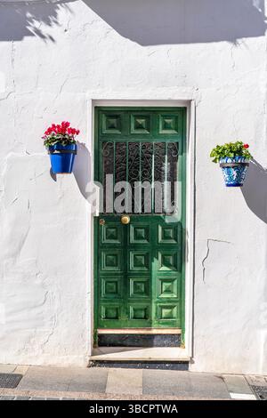 Green door and flowers in the colorful pots on white houses in Mijas, Pueblos Blancos, White Villages,  Spain Stock Photo