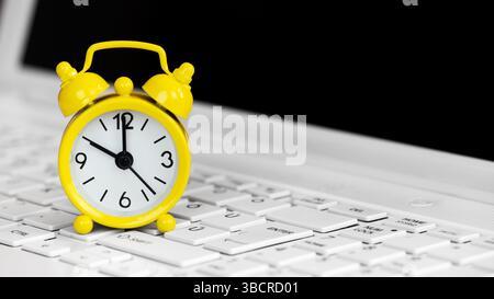Alarm clock on a laptop keyboard, deadline concept. Background with copy space. Stock Photo