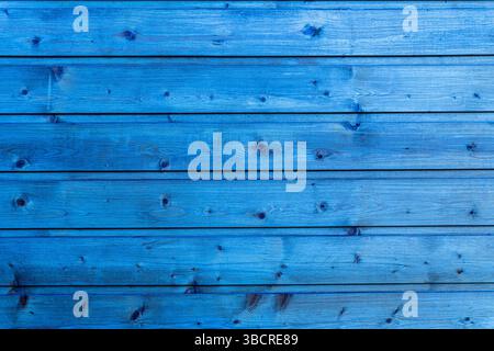 Horizontal planks of wood painted in bright blue with visible grain and knots in natural light. Stock Photo