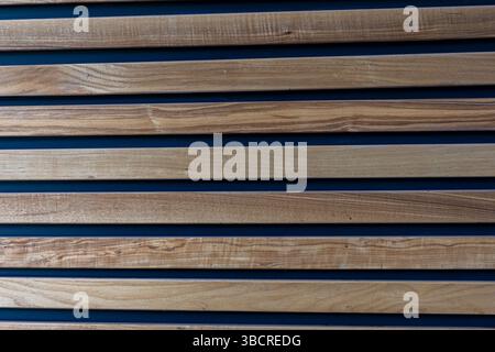 Natural wood slats with dark gaps in a horizontal pattern, creating a modern architectural wall texture suitable for design and construction use. Stock Photo