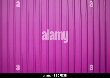 Vertical ribbed pink metal surface with light shadowing, perfect for modern industrial backgrounds or design use. Stock Photo