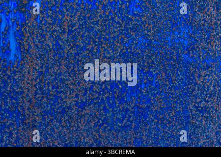 Close-up of a deep blue painted metal sheet with scattered rust and corrosion, perfect for industrial or grunge-inspired backgrounds. Stock Photo