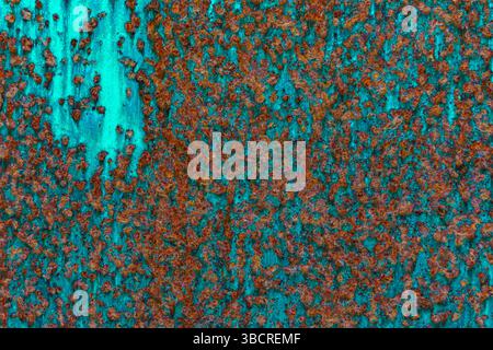 Close-up of teal-painted metal with scattered rust and corrosion, blending cool tones with earthy textures for industrial or abstract design use. Stock Photo