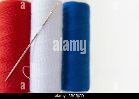 Studio shot of needle and spools of red, white and blue thread Stock Photo