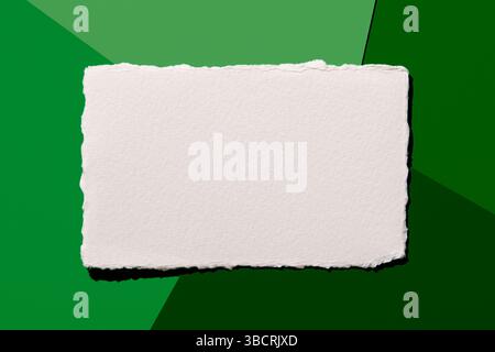 Torn white paper on green background Stock Photo